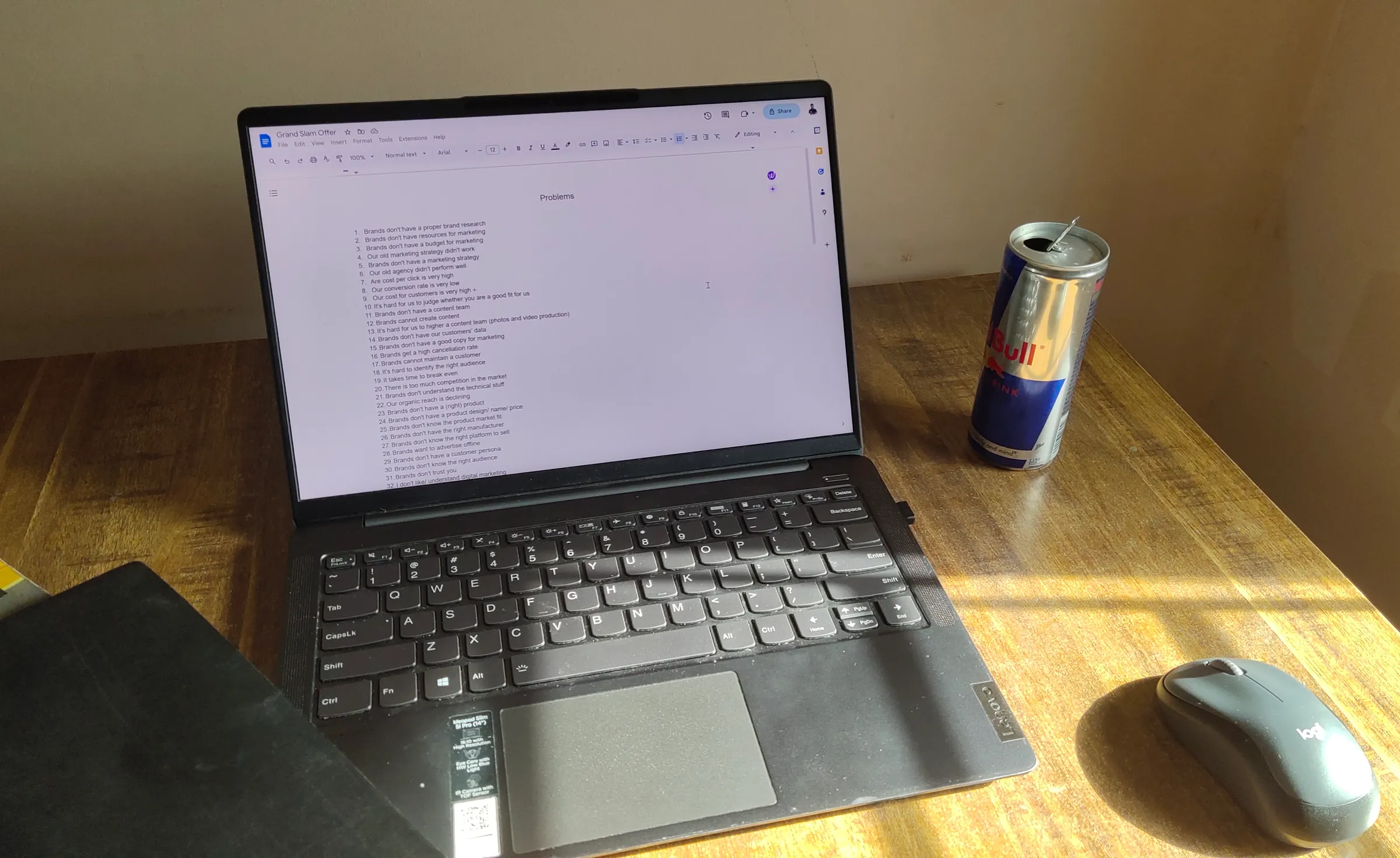 The desk where Remotely Outsource started: a laptop open on a to-do list, a mouse and an energy drink in the afternoon sun